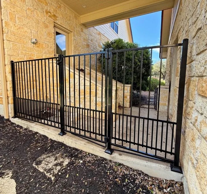Black metal double pedestrian gates by stone house